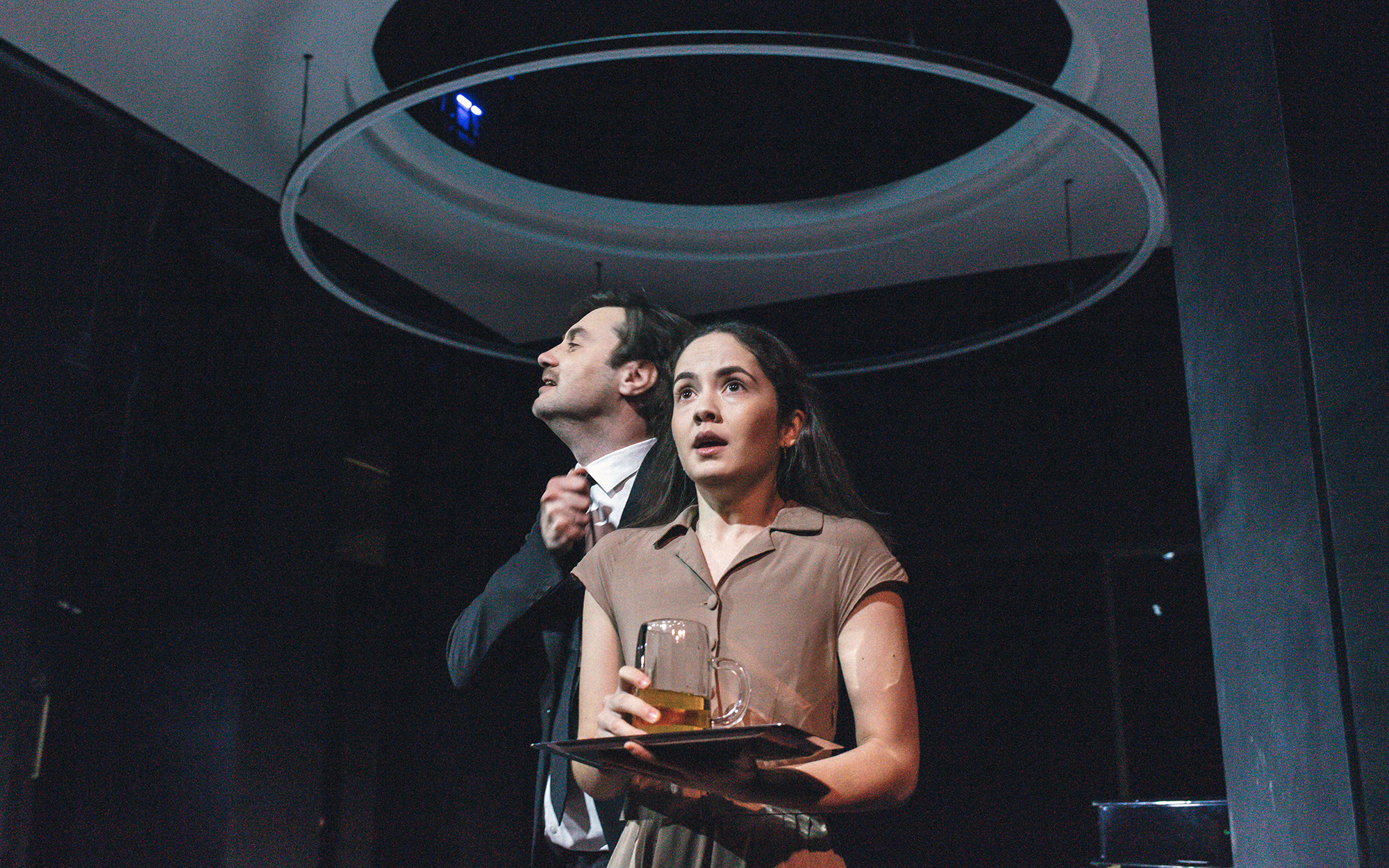 Lopahin Jermolaj Aleksejevič (Branko Jordan) si zateguje kravato pri ovratniku srajce, pred njim stoji Dunjaša (Lara Wolf), vidno vznemirjena, v roki drži pladenj s kozarcem piva.