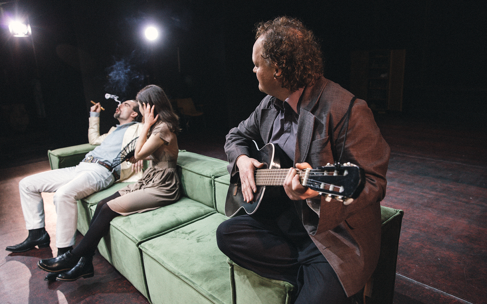 Jaša (Gregor Gruden) sedi na veliki zeleni zofi in kadi cigaro, proti njemu se v zapeljivi kretnji nagiba Dunjaša (Lara Wolf). Dogajanje s kitaro spremlja Jepihodov Semjon Pantelejevič (Gašper Jarni).