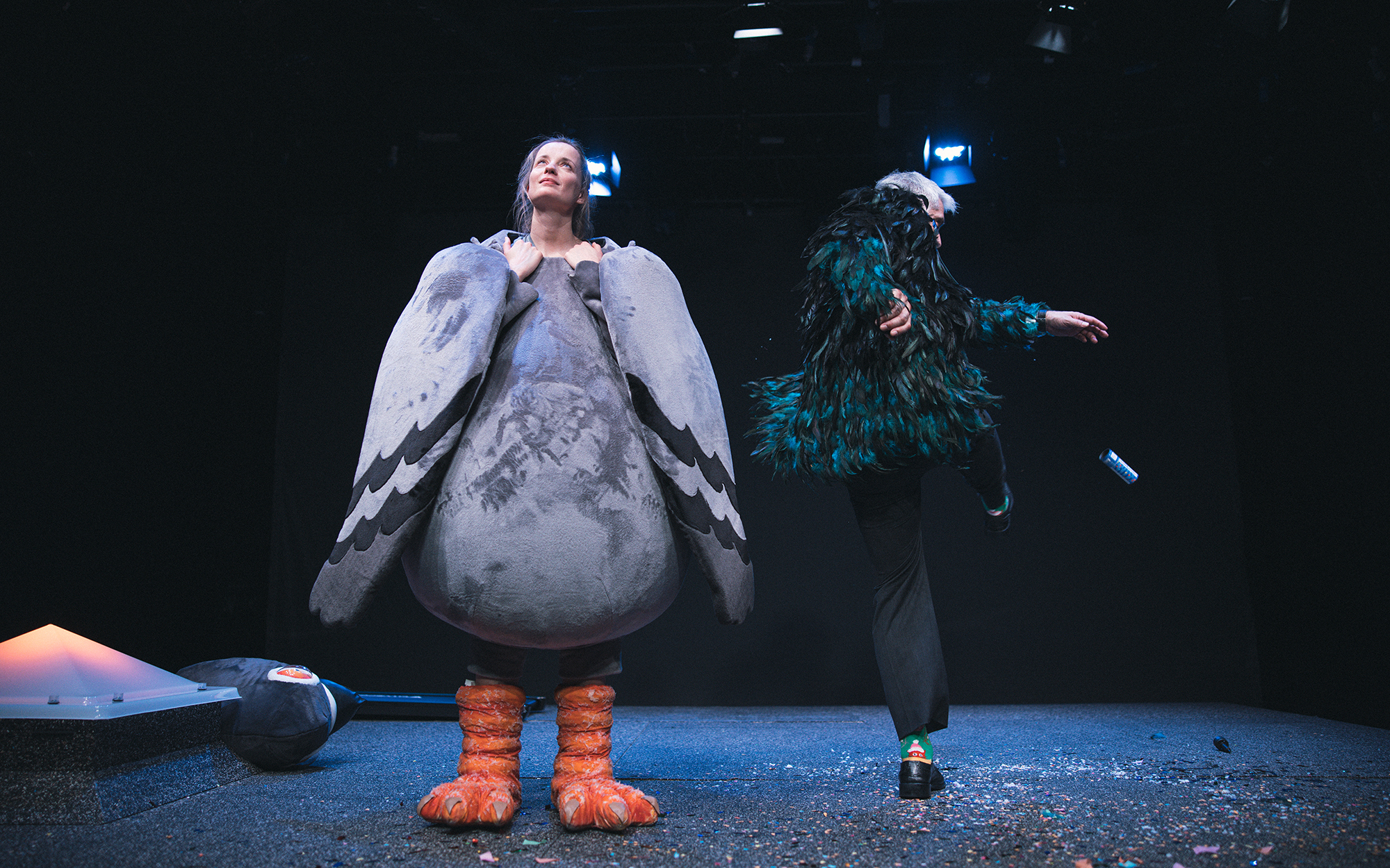 Na levi strani odra se smehlja Ona (Ajda Smrekar), kostumirana v goloba, glavo ima odkrito. On (Sebastian Cavazza) ob njej pleše. Avtor fotografije: Peter Giodani.