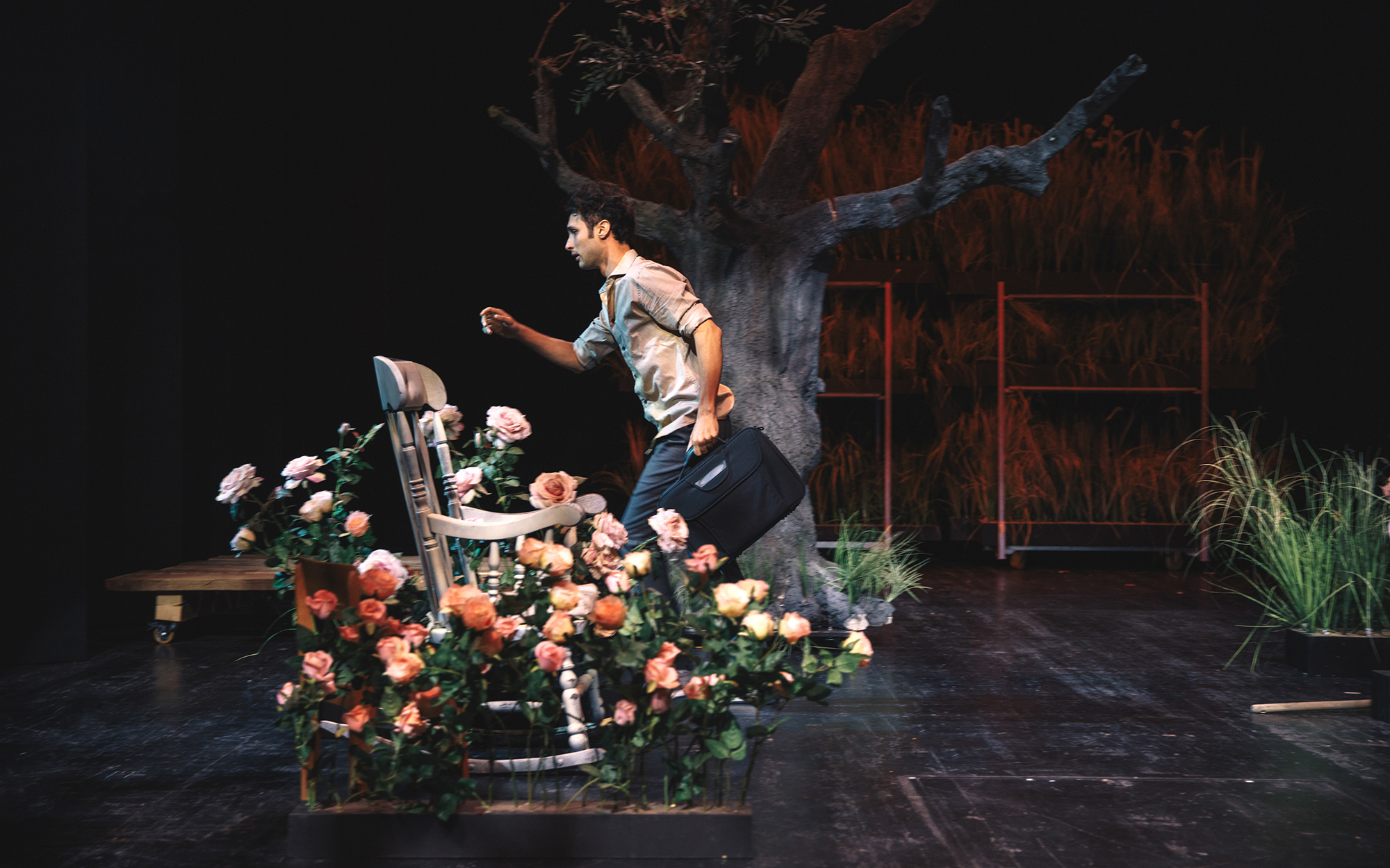 Ben (Voranc Boh) hiti čez vrt, v roki nosi aktovko. Pred njim so gugalnik in vrtnice, za njim golo drevo. Avtor fotografije: Peter Giodani. 