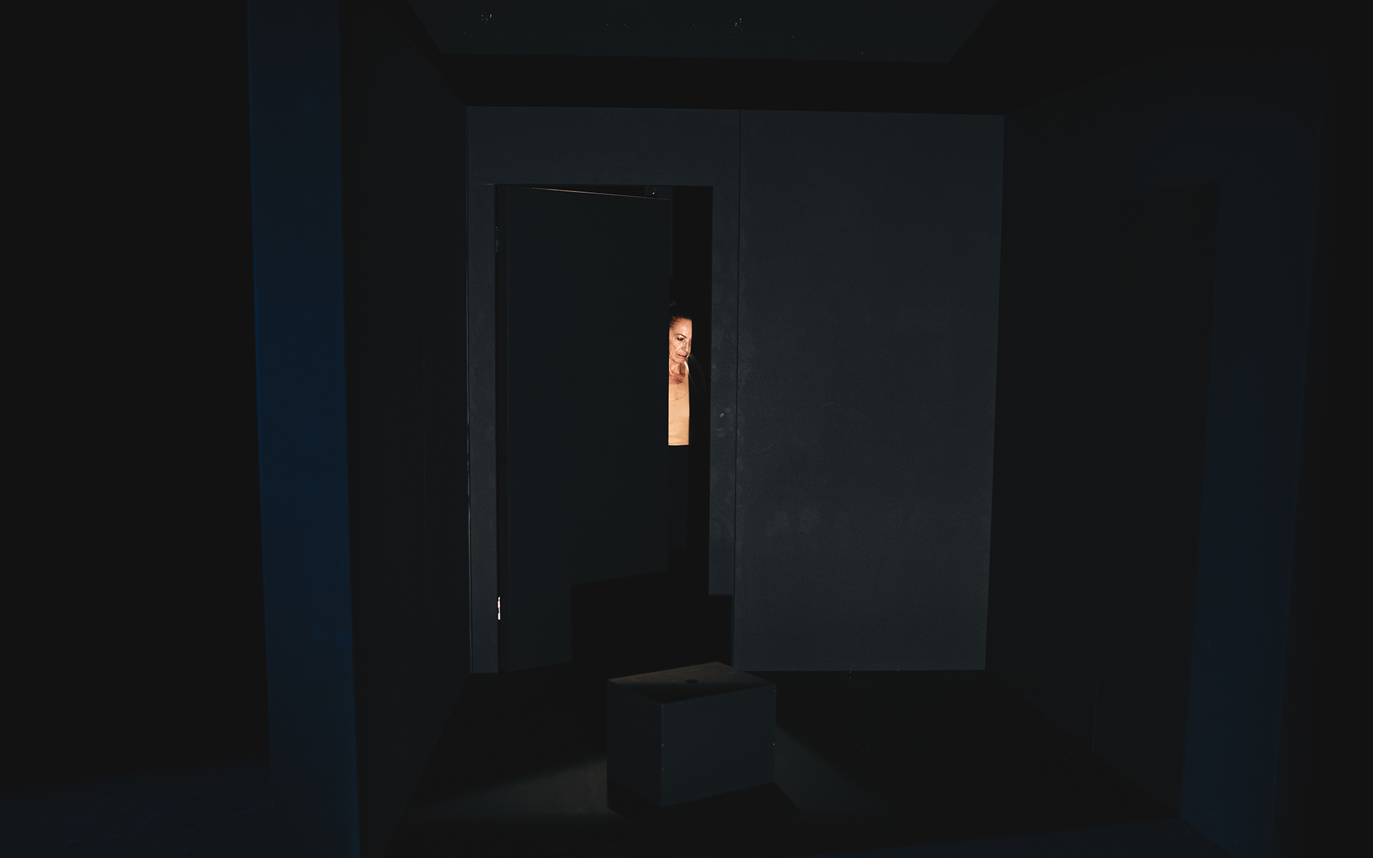 Jožica Avbelj odpira vrata črnega okvirja, ki je del scene.
