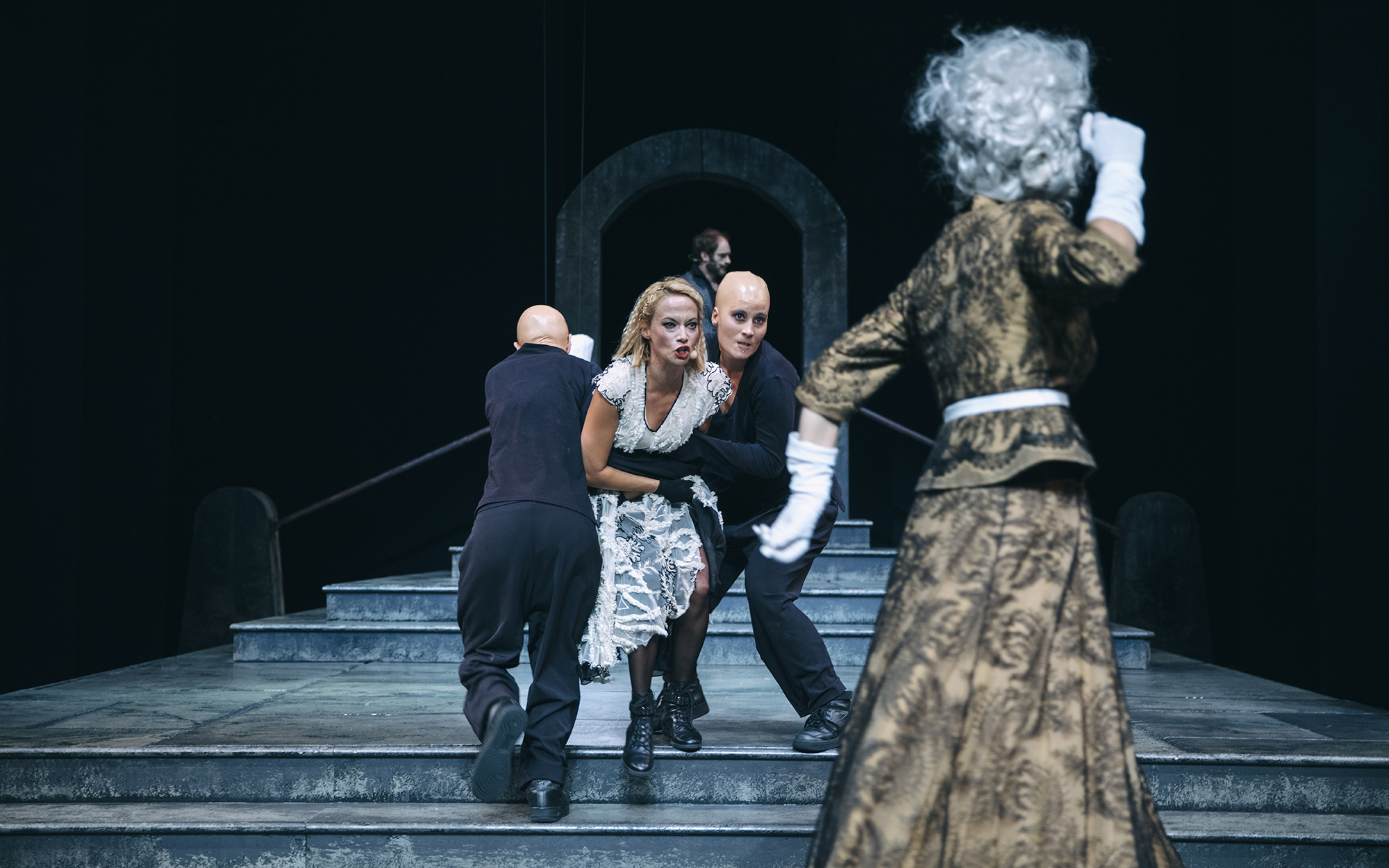 Gargojla (Neža Blažič in Veronika Valdes) vlečeta Turandot (Viktorija Bencik Emeršič) stran od Kraljice mati (Mirjam Korbar), ki žuga za njimi s pestmi.  Avtor fotografije: Peter Giodani.