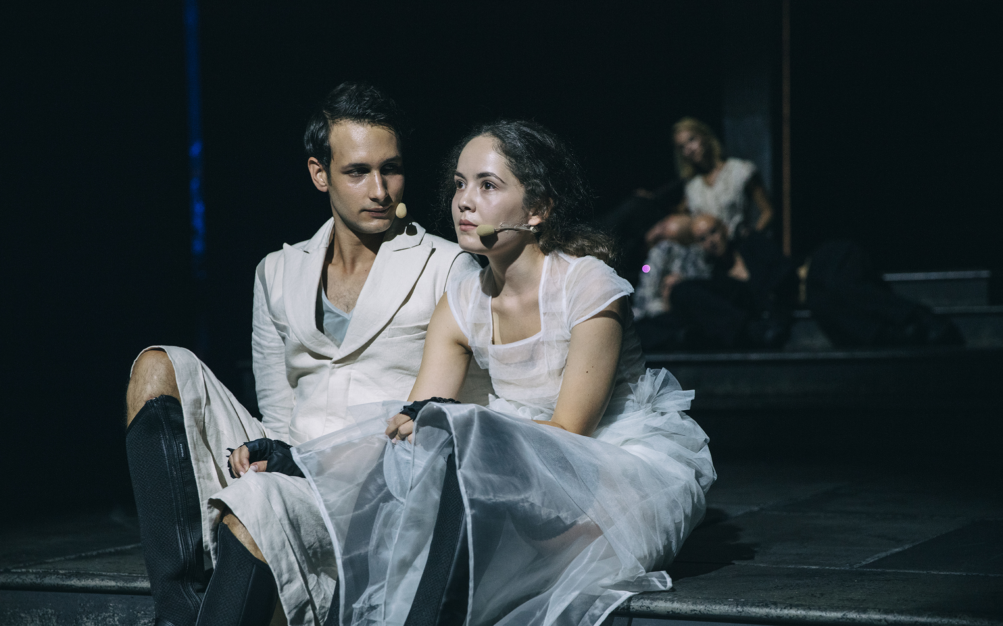 Mladi Kalaf (Voranc Boh) sedi na stopnicah in gleda Mlado Turandot (Lara Wolf), ki sedi poleg njega in zre v daljavo. Avtor fotografije: Peter Giodani.